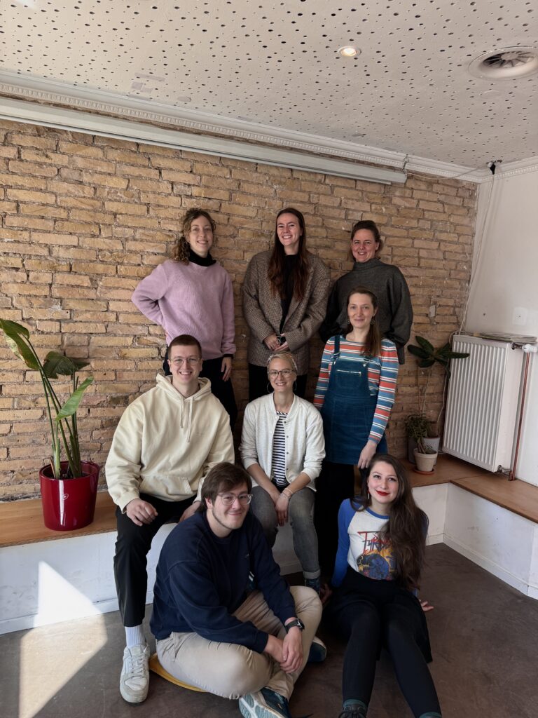 Das SEEd Team, 8 junge motivierte Menschen stehen als Gruppe vor einer Steinwand